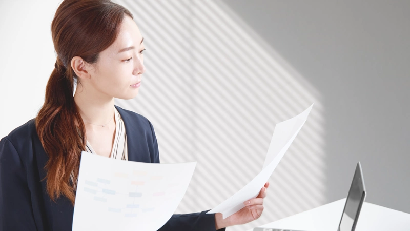 納品書を手にする女性とパソコン